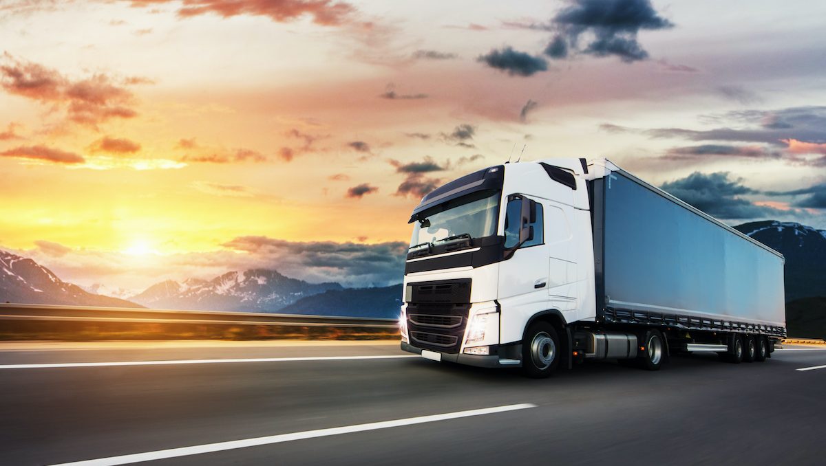 European truck vehicle on motorway with dramatic sunset light. Cargo transportation and supply theme.